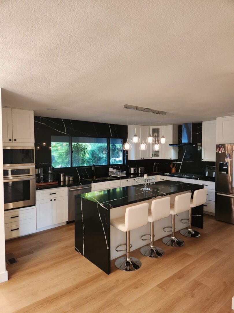 A kitchen with black and white cabinets, an island bar and a stove.